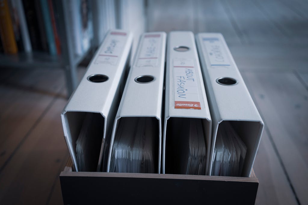 From above of similar folders with plastic sleeves and titles on surface in wooden box on floor